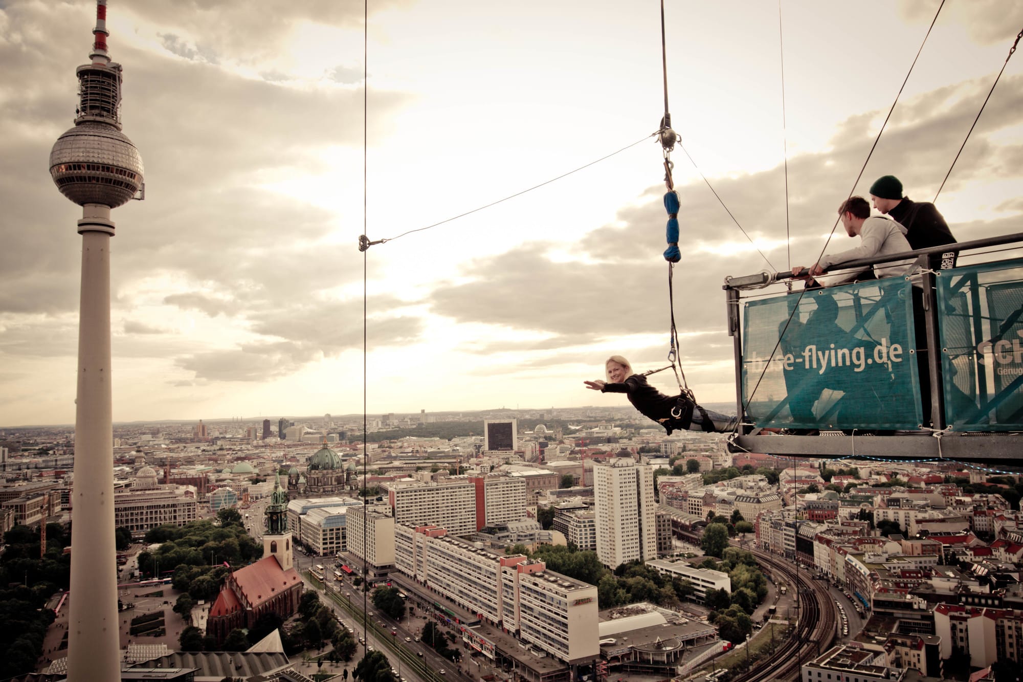 Mann hängt lächelnd am Base Flyer mit dem Fernsehturm Berlins im Hintergrund