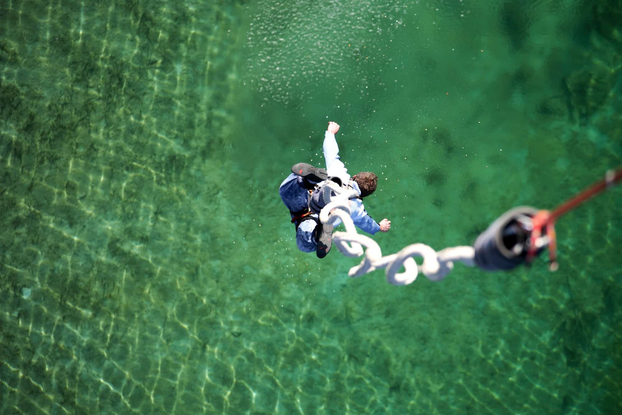 Mann springt Bungee über grünblauem Wasser der Regattaanlage Oberschleißheim